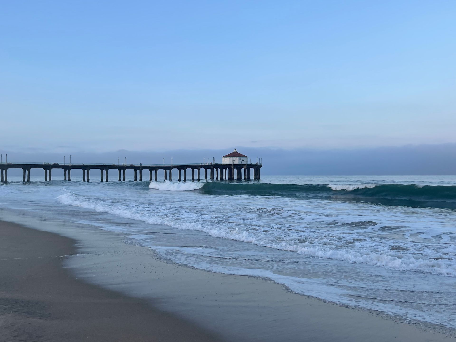 a pier leading into the ocean with waves crashing on the beach
