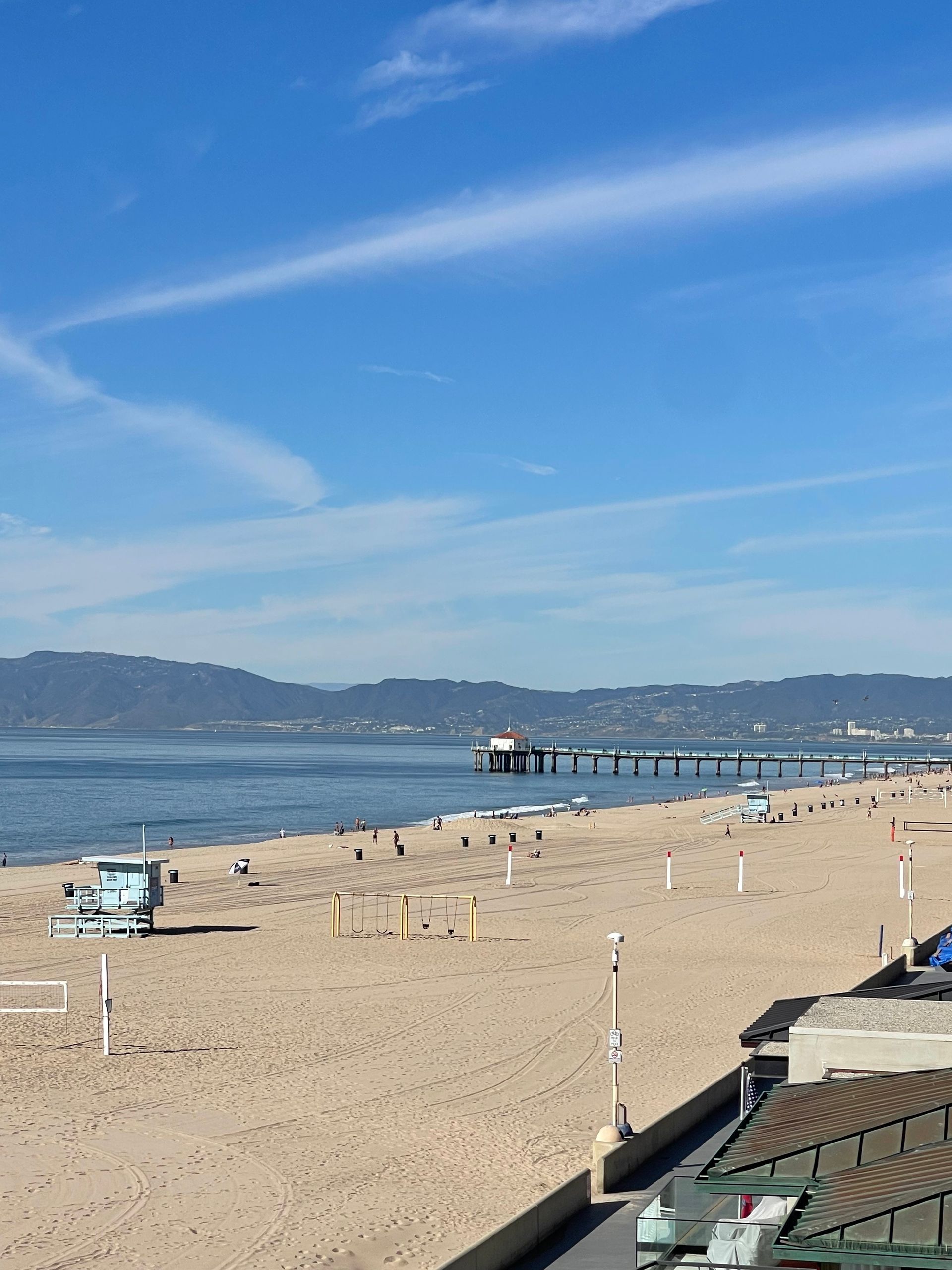 a beach with a lifeguard tower and a pier in the background