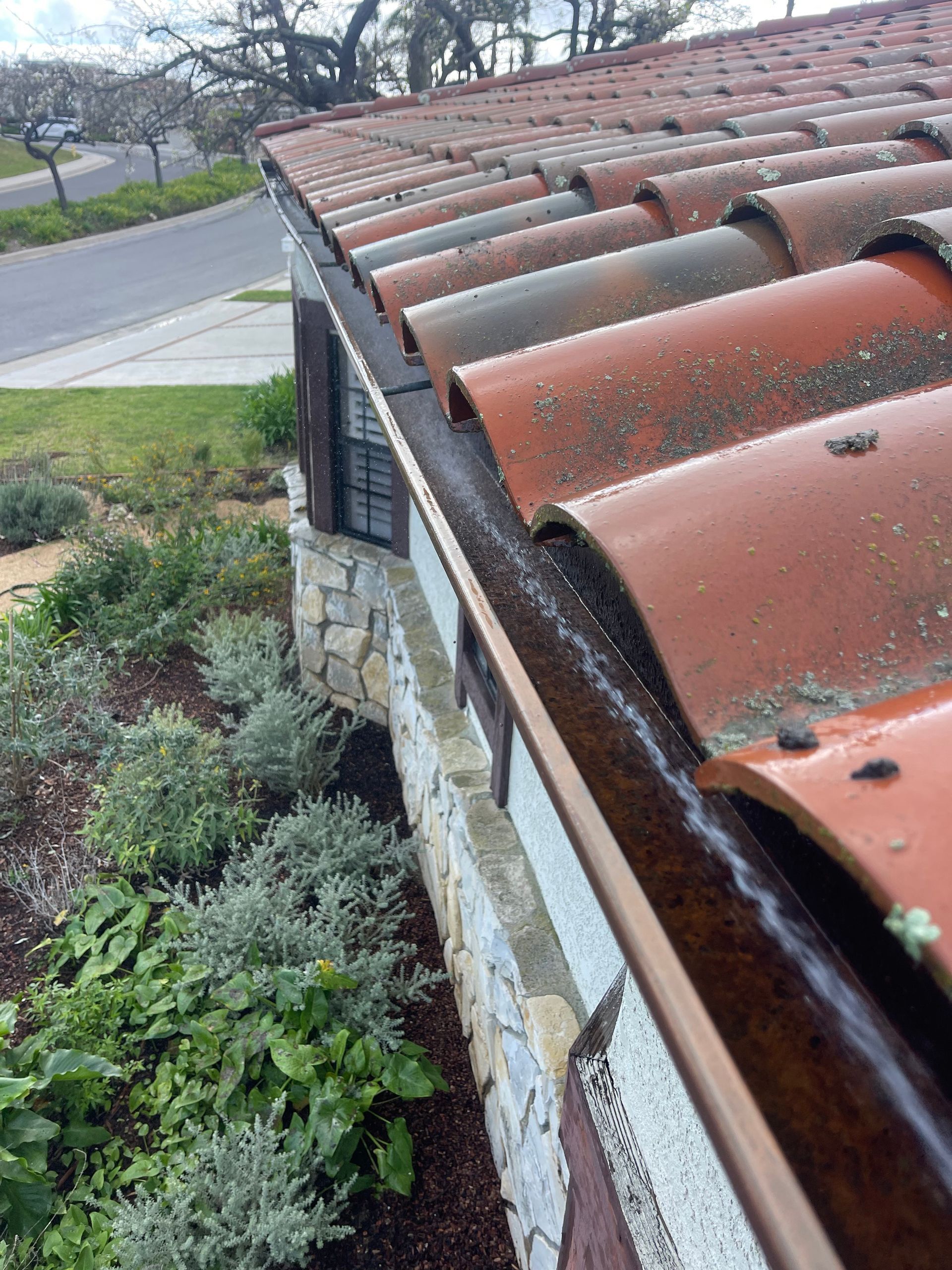 a gutter on the side of a house with a tiled roof