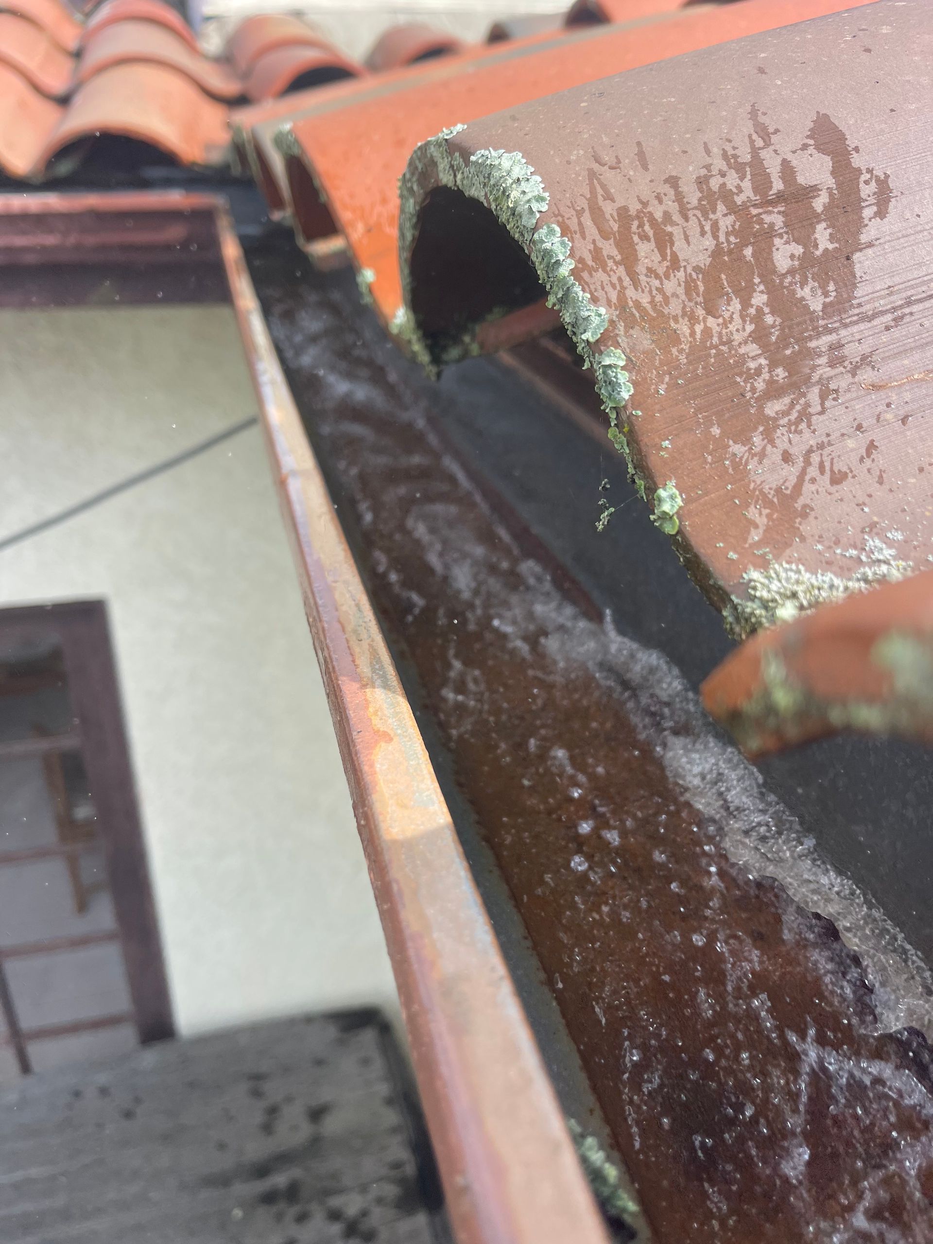 a close up of a gutter with a roof in the background