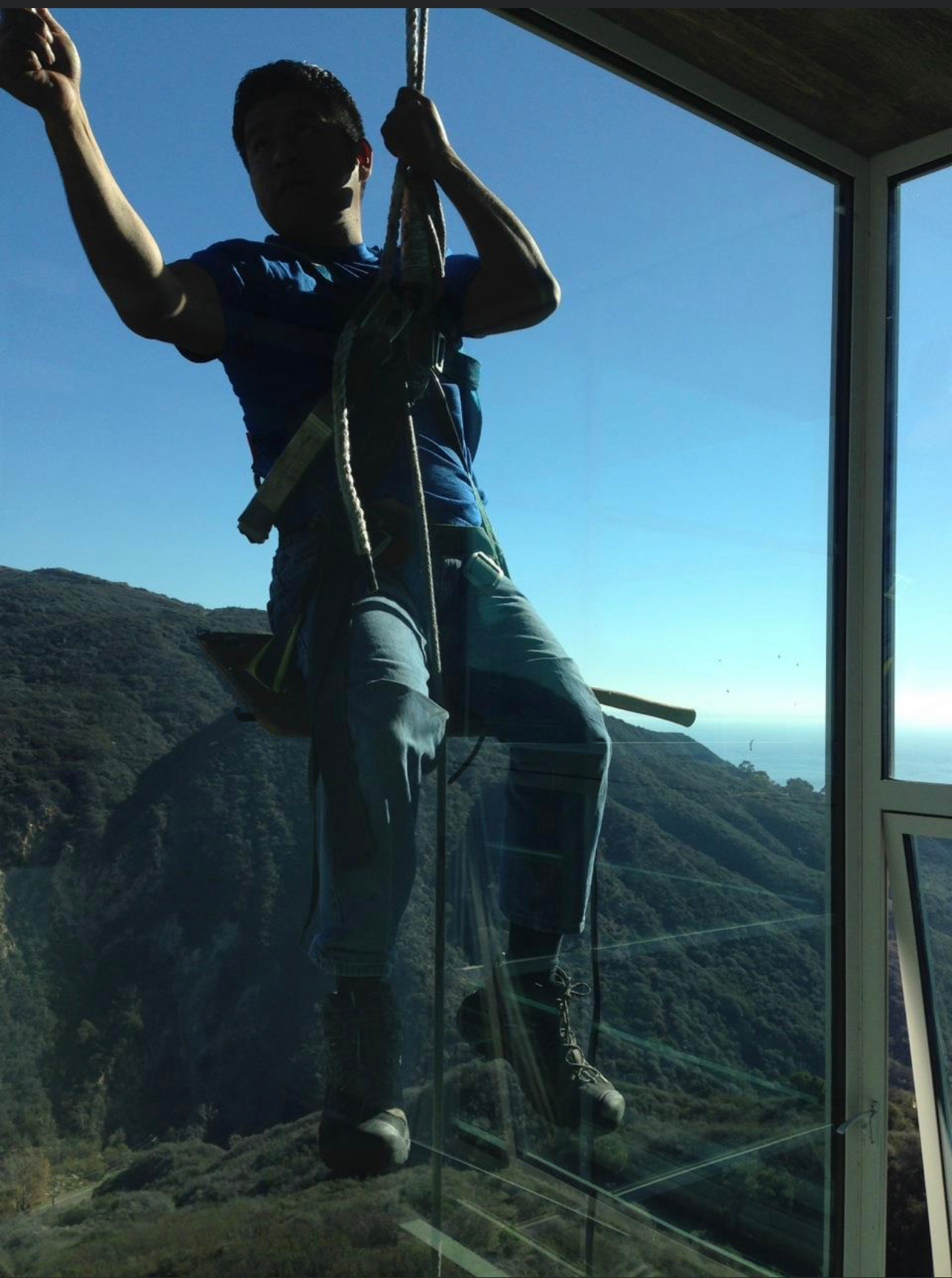 a man hanging on a building while cleaning the windows