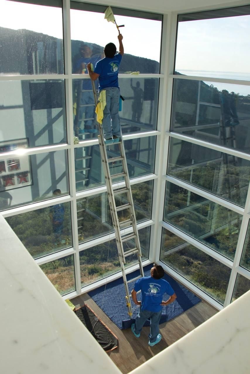 a man standing on a ladder cleaning a window