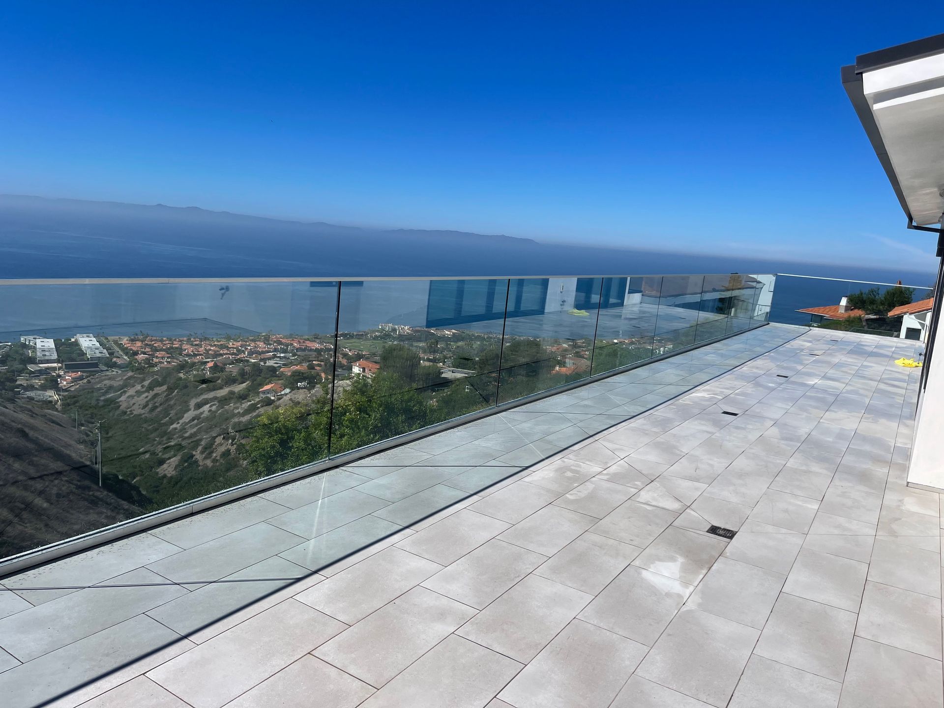 a balcony with a glass railing overlooking the ocean