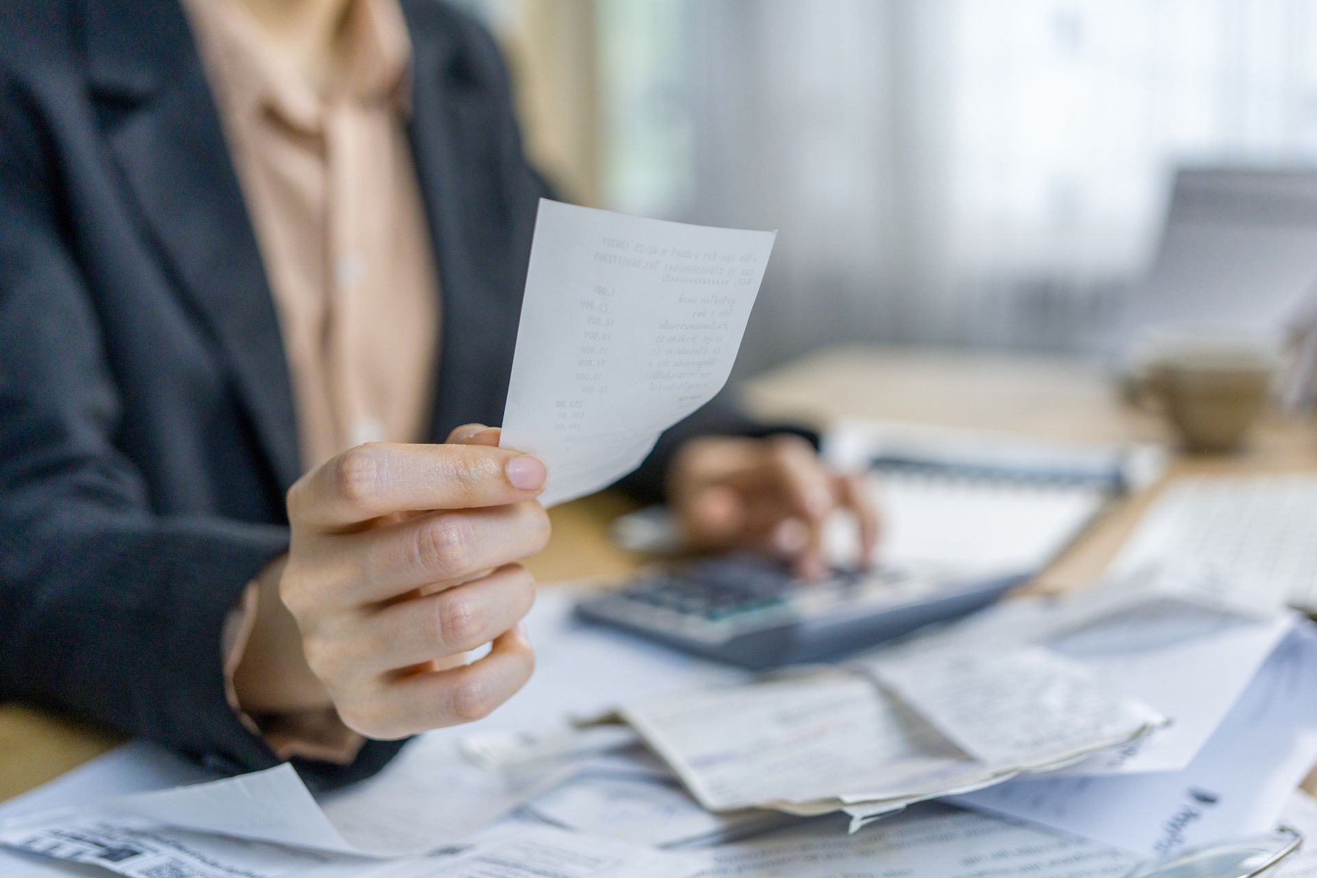 A Woman Is Sitting at A Desk Holding a Piece of Paper.
