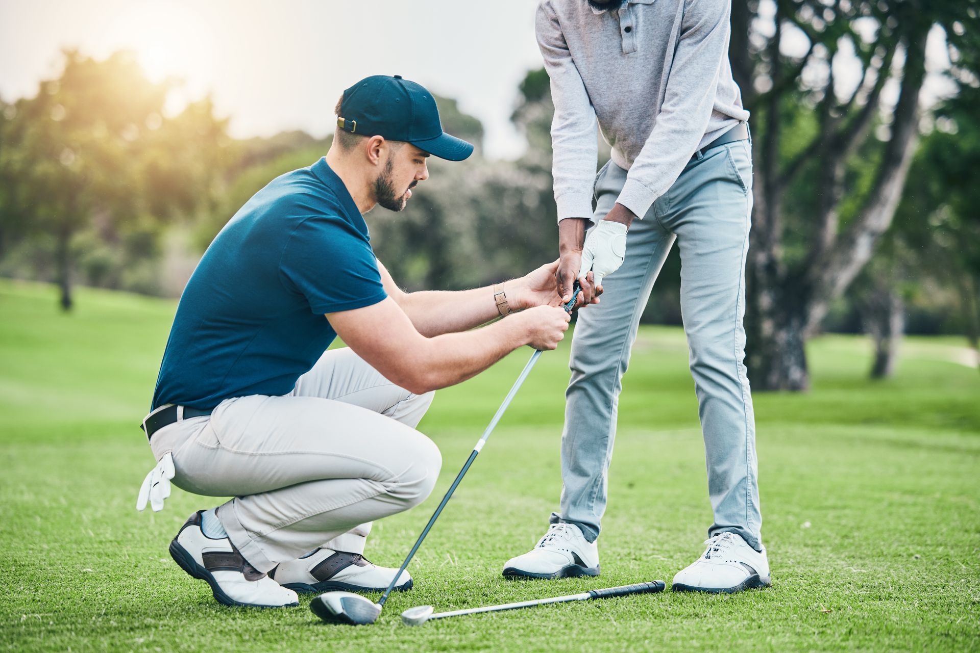 A man is teaching another man how to swing a golf club on a golf course.