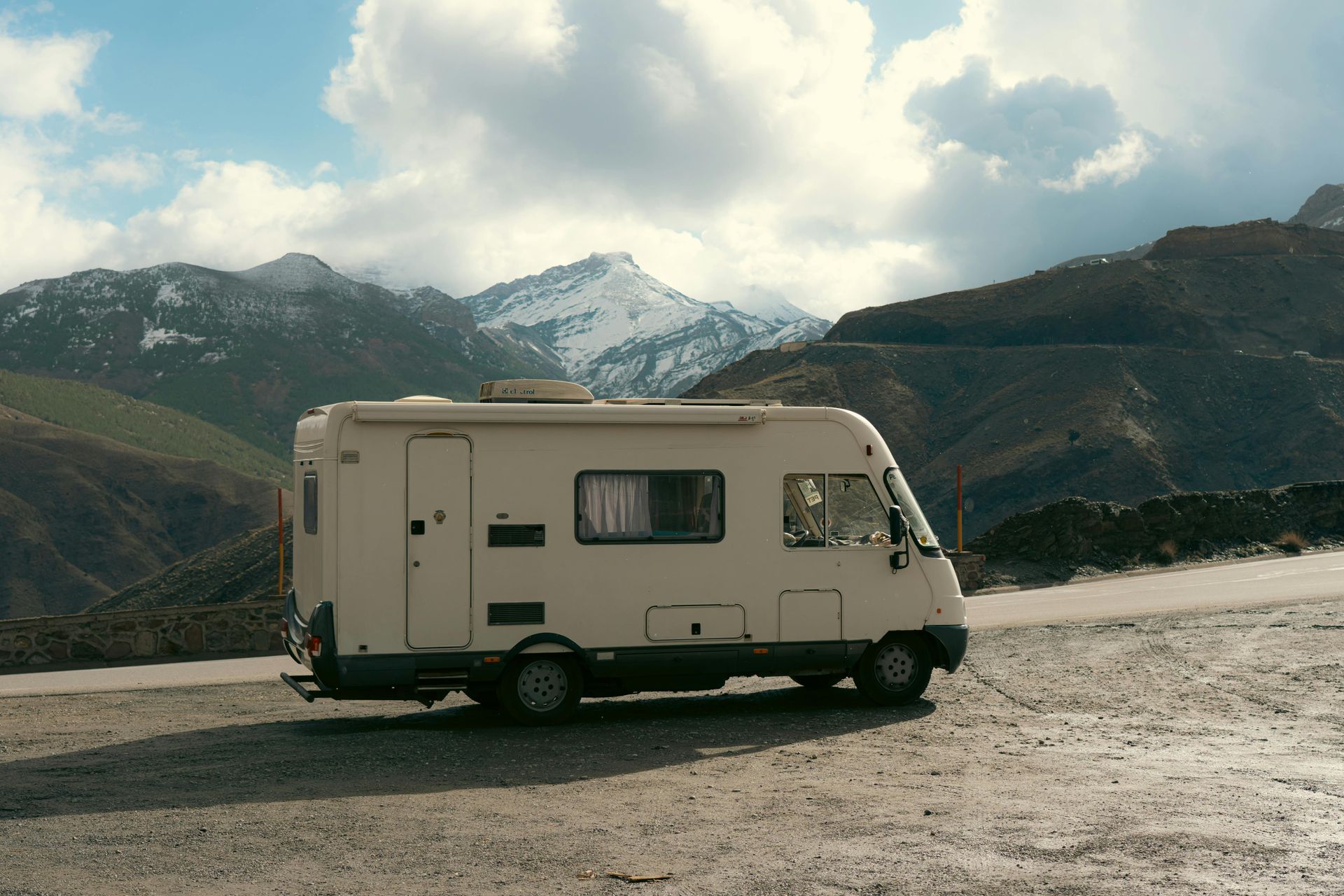 A white rv is parked on a dirt road with mountains in the background