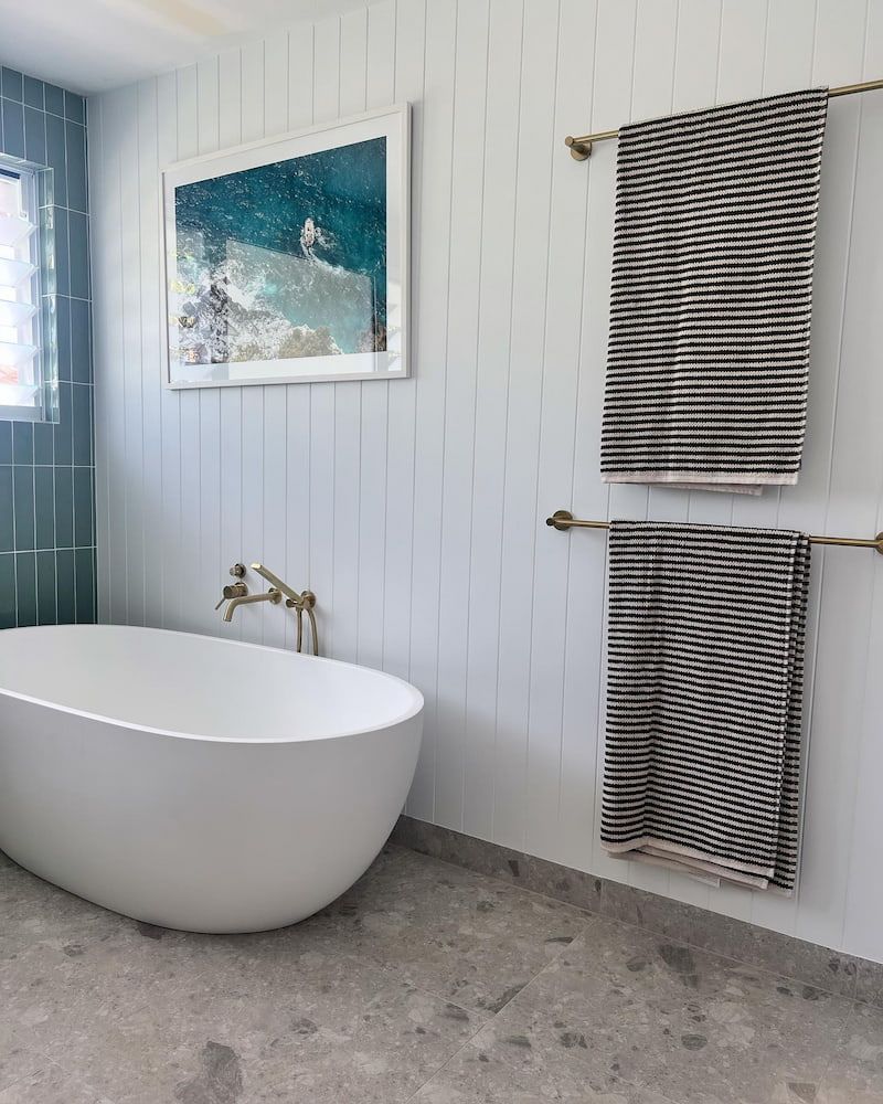A Bathroom With A Bathtub And Two Towels Hanging On The Wall — Old Mate Plumbing Co in Hollywell, QLD