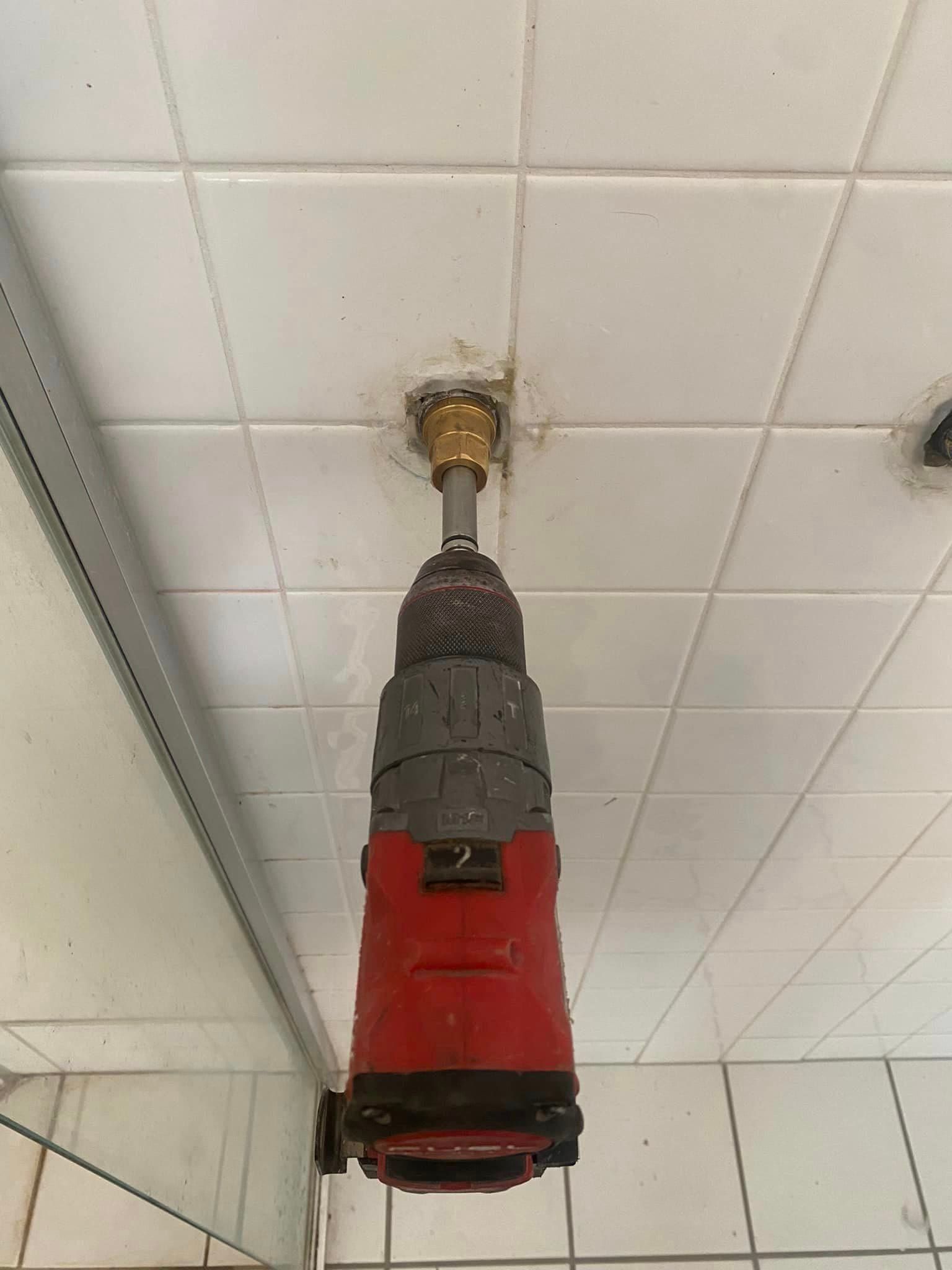 A Red Drill Is Hanging From The Ceiling In A Bathroom — Old Mate Plumbing Co in Hollywell, QLD