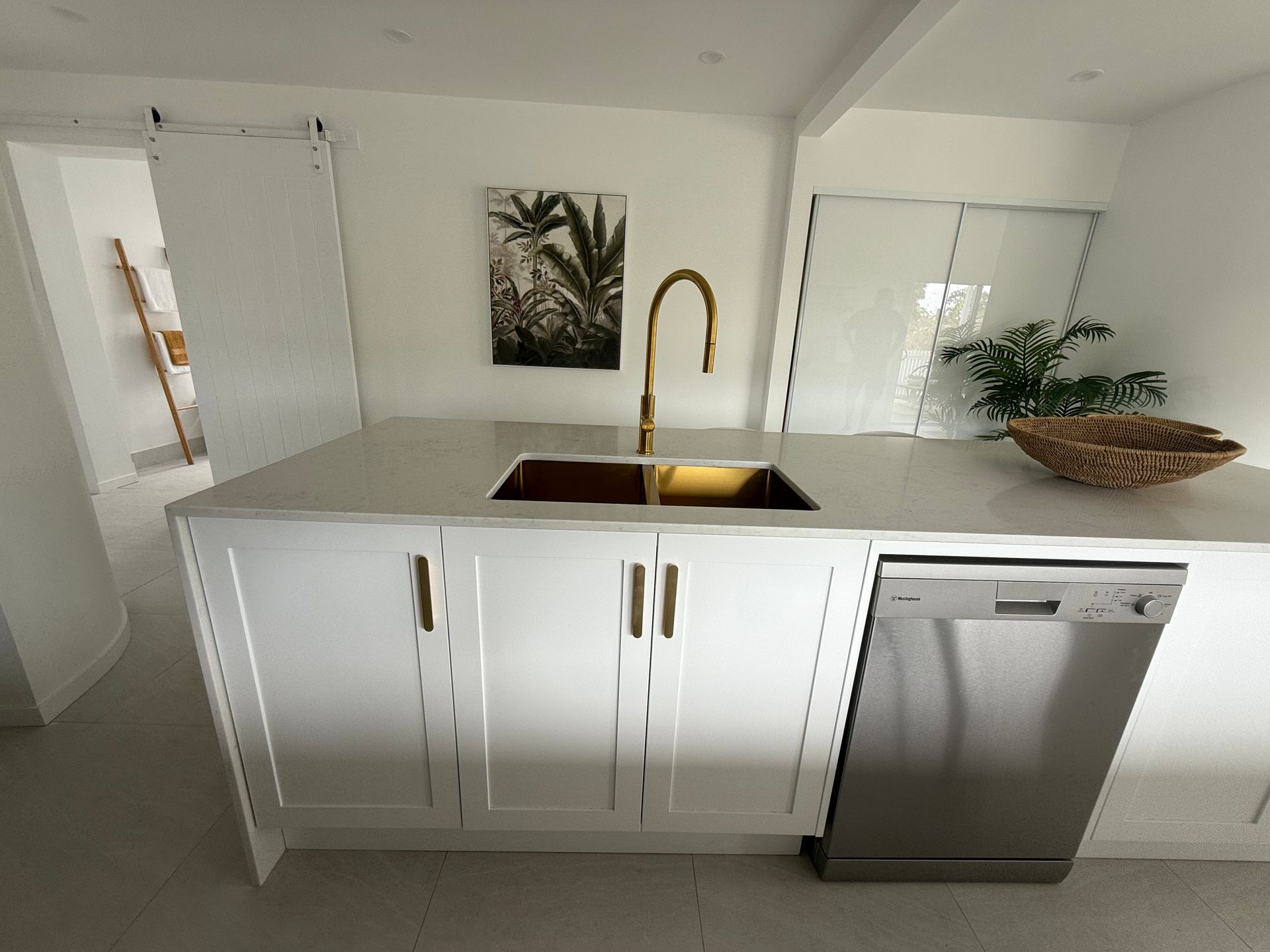 A White Kitchen With Sink And Painting On The Wall — Old Mate Plumbing Co in Hollywell, QLD