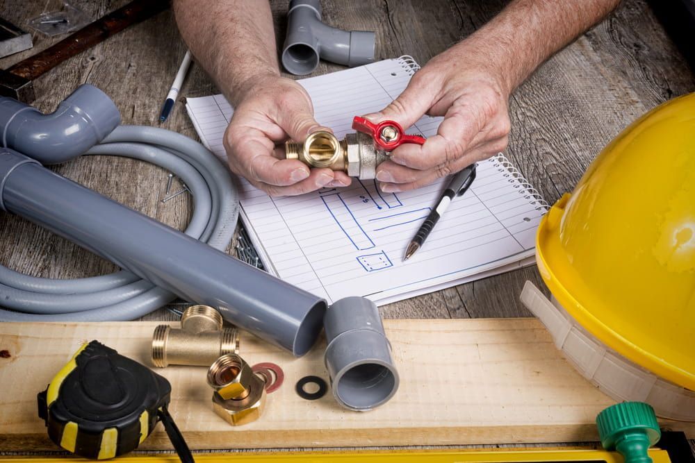 A Plumber Is Working On A Pipe On A Wooden Table — Old Mate Plumbing Co in Southport, QLD