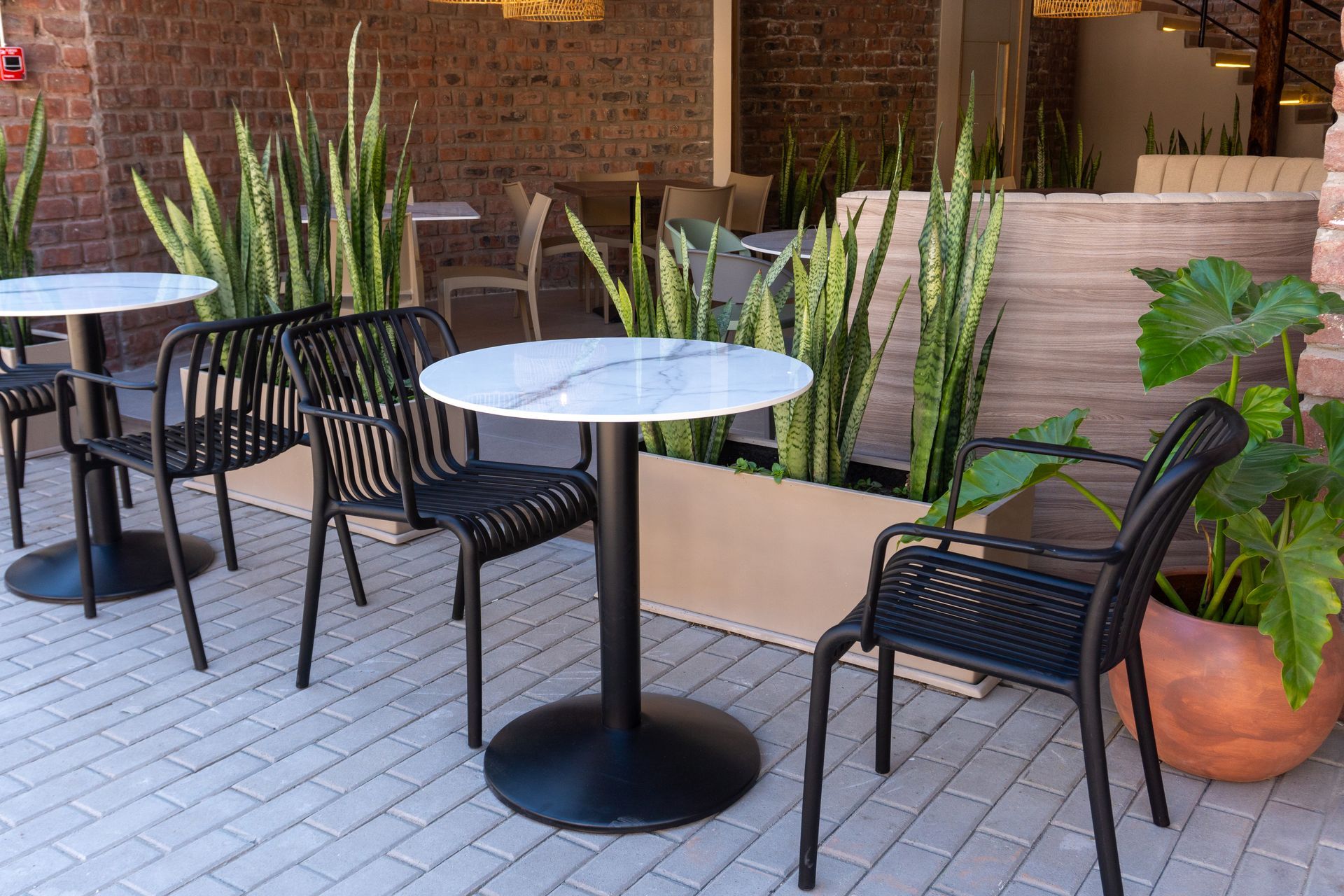 A patio with tables and chairs and potted plants.