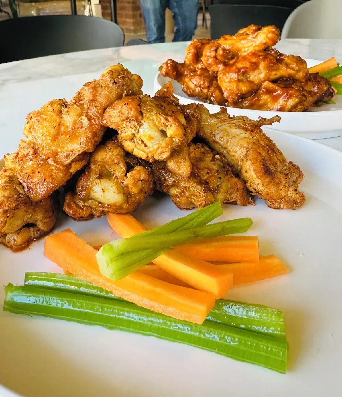 A white plate topped with chicken wings carrots and celery