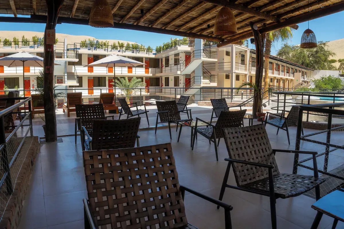 A patio with chairs and tables under a wooden roof