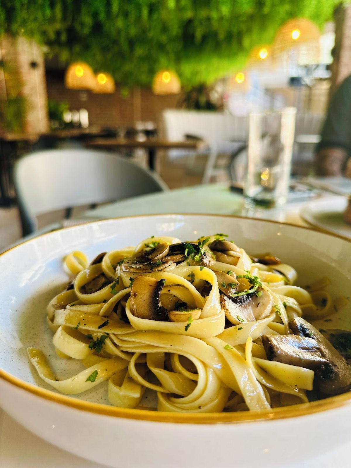 A bowl of pasta with mushrooms on a table in a restaurant.