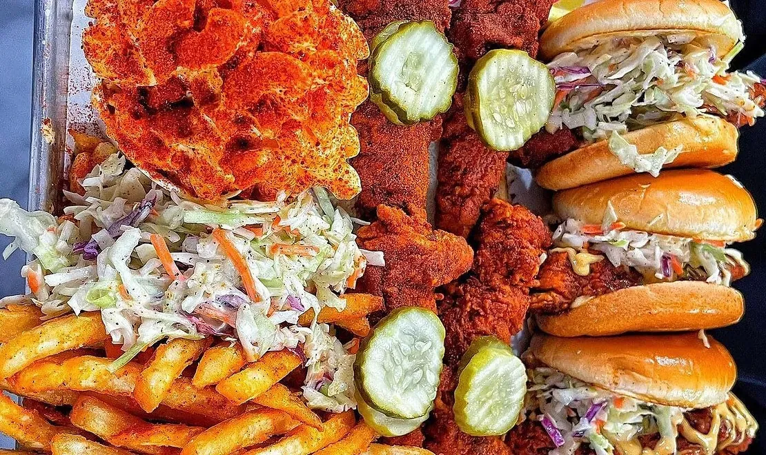 A tray of fried chicken , french fries , coleslaw , pickles and sandwiches.