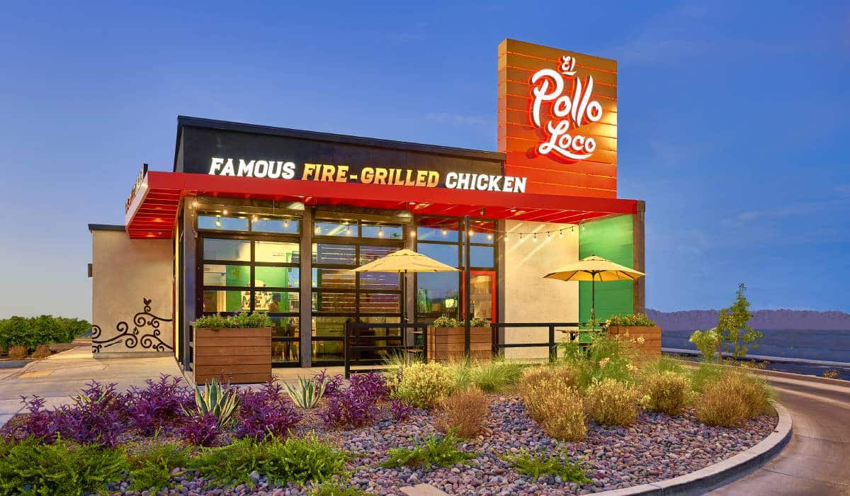 A pollo loco restaurant with umbrellas and flowers in front of it.