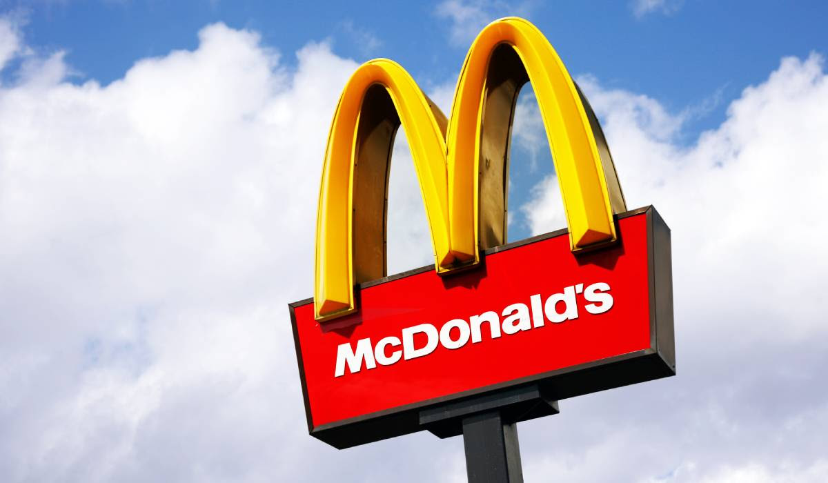 A mcdonald 's sign against a blue sky with clouds