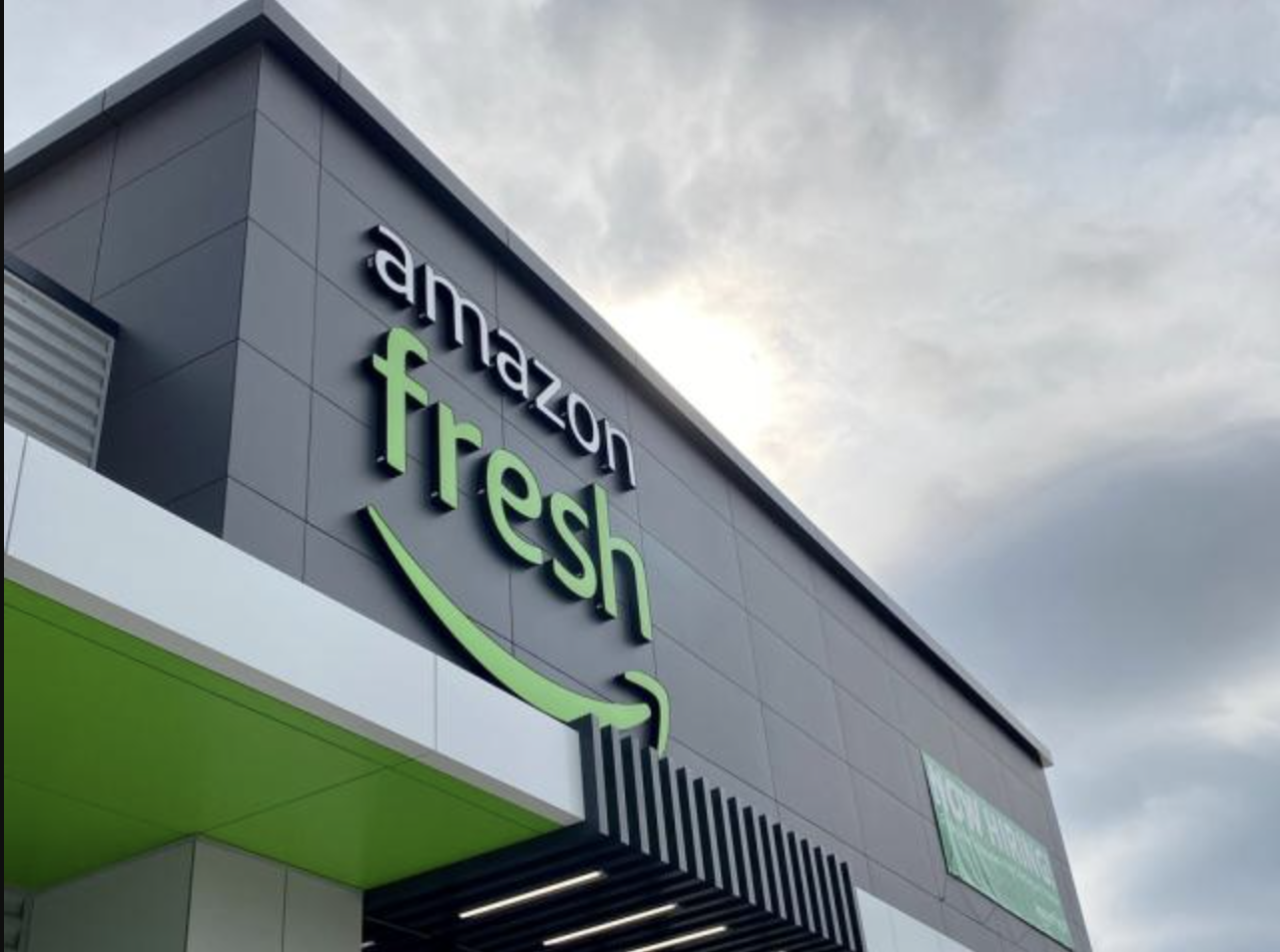 The front of an amazon fresh store with a cloudy sky in the background