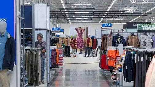 A woman is standing in the middle of a clothing store.