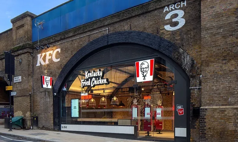 A kfc restaurant is located under a bridge.