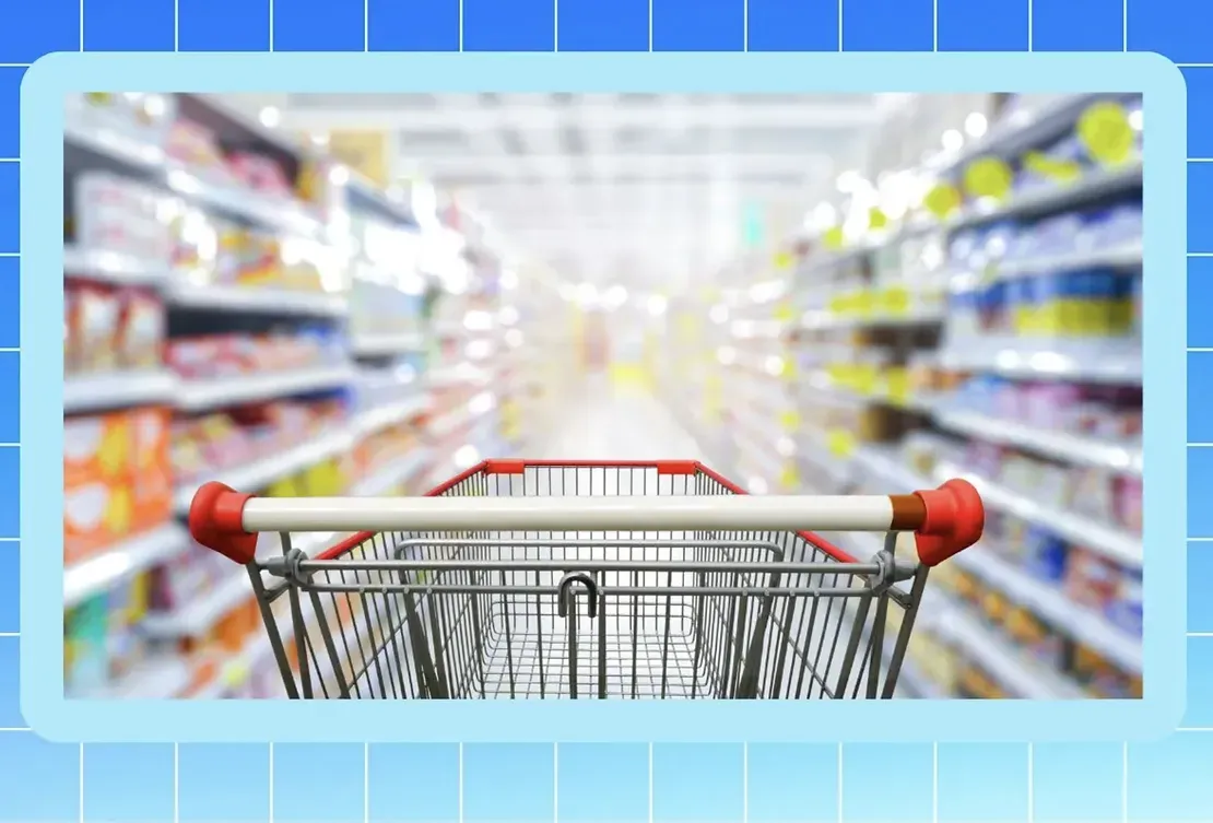 A shopping cart is sitting in the middle of a supermarket aisle.