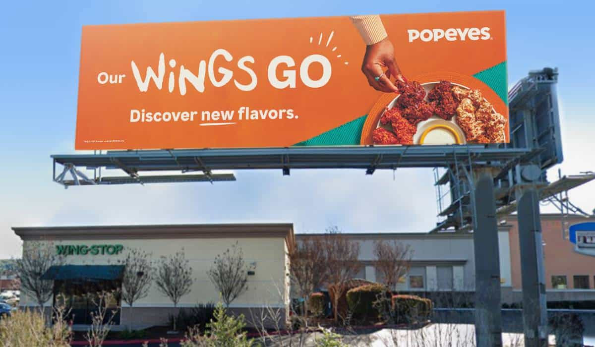 A billboard for popeye 's wings go is above a building