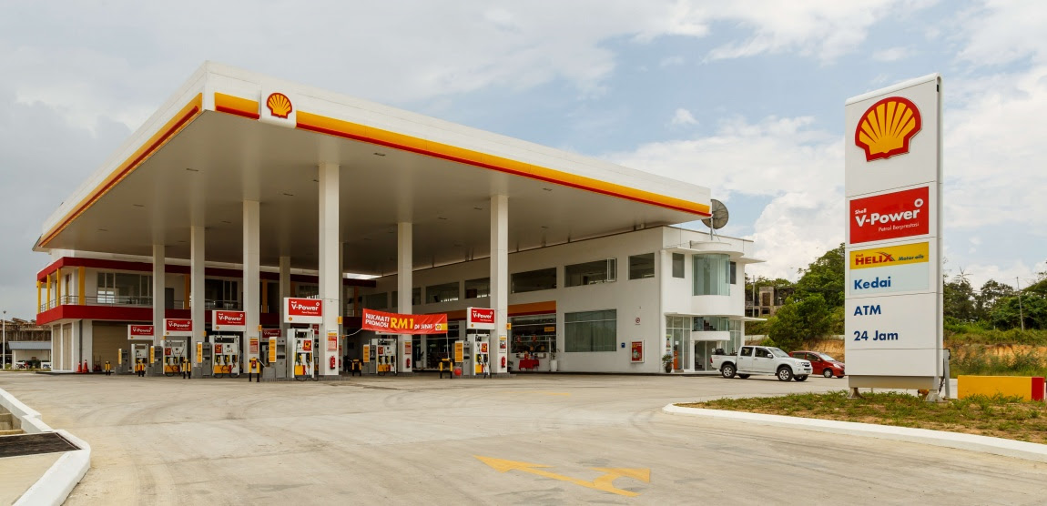 A shell gas station with a car parked in front of it.