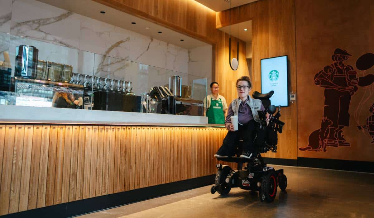 A man in a wheelchair is standing in front of a counter in a restaurant.