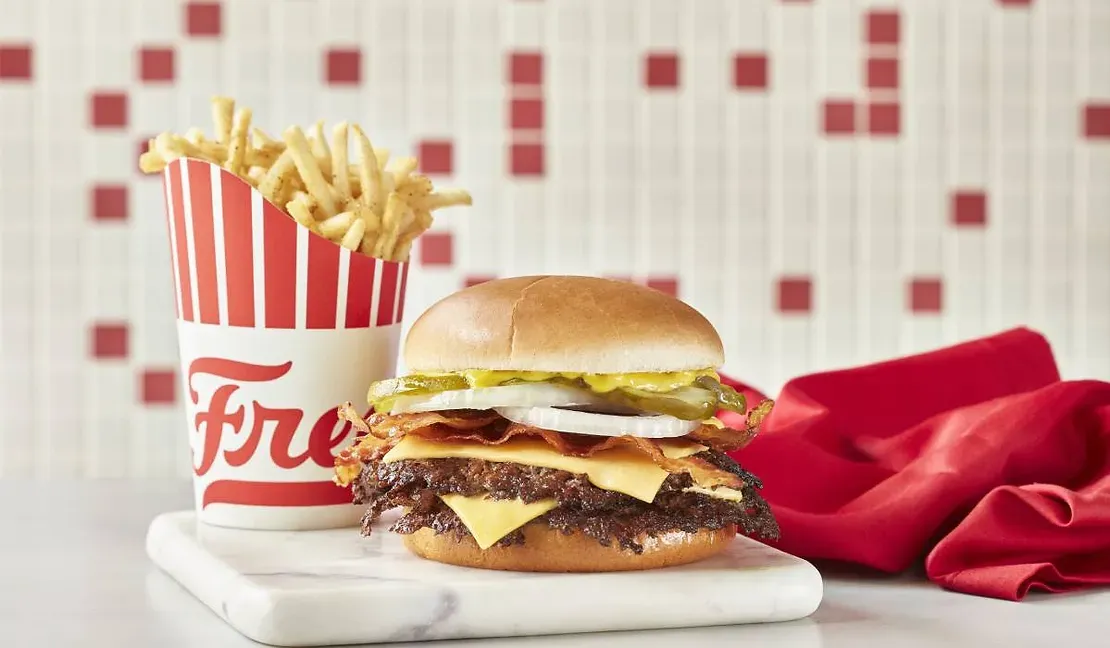 A hamburger and a cup of french fries are on a table.