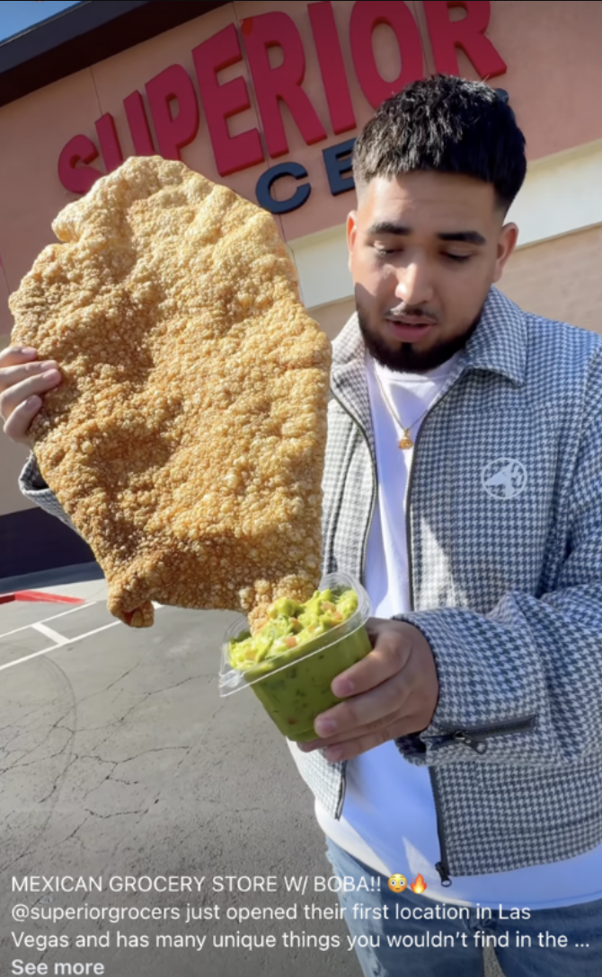 A man is holding a large piece of food in front of a store that says superior