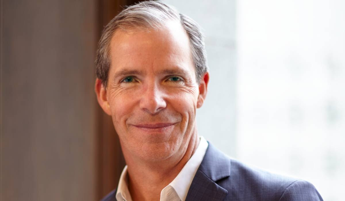 A man in a suit and white shirt is smiling for the camera.