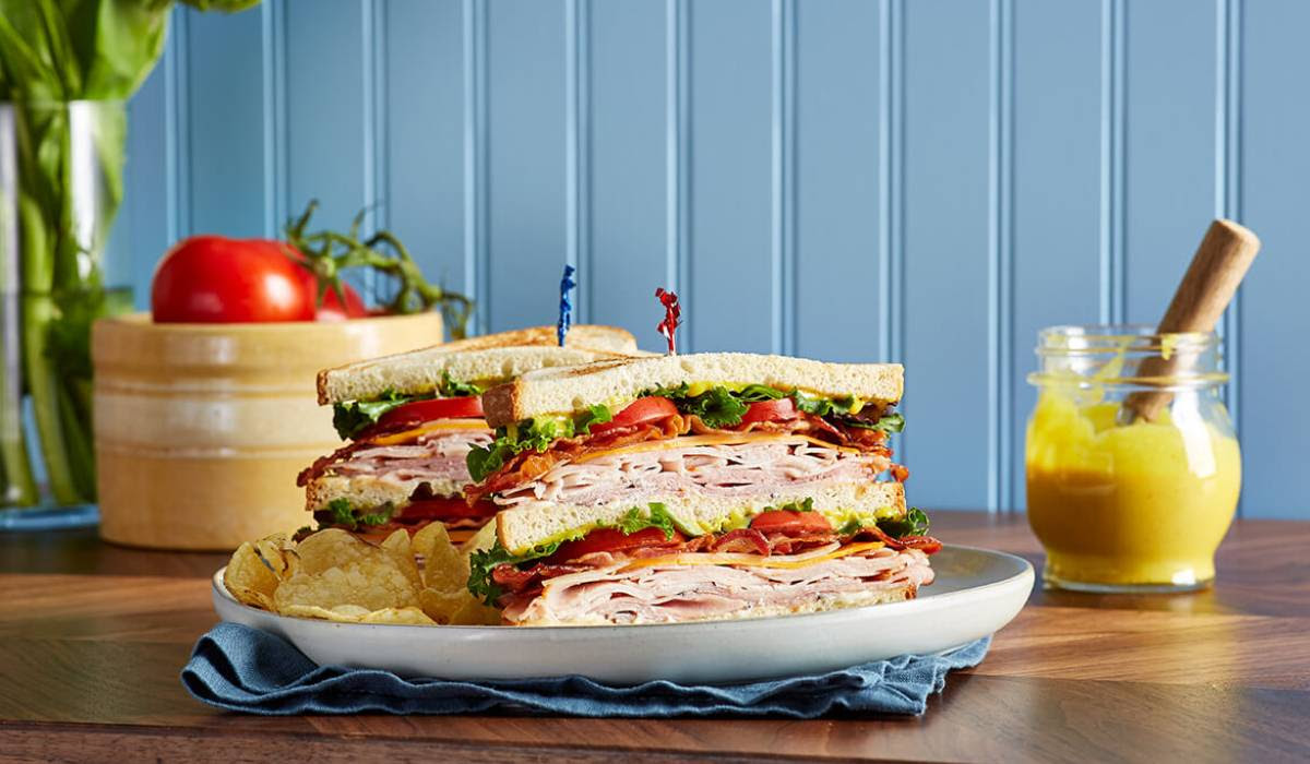 A club sandwich is stacked on top of each other on a plate on a table.