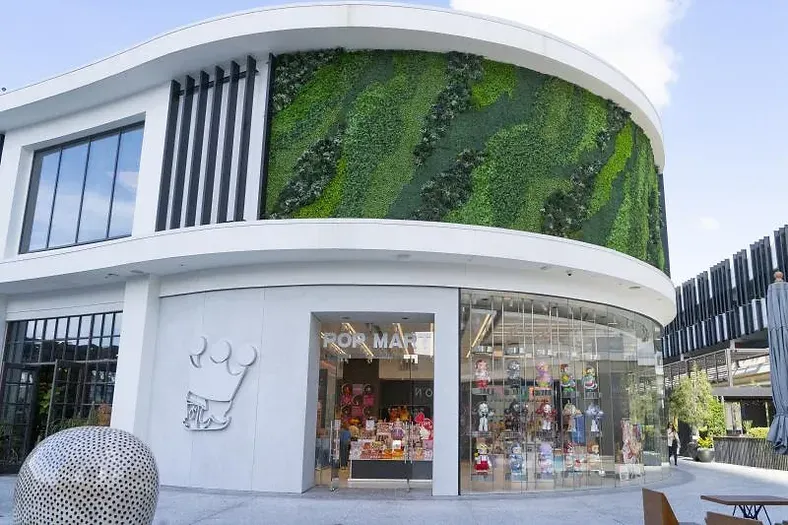 A large white building with a green wall on the side of it.