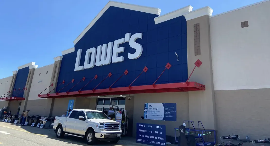 A white truck is parked in front of a lowe 's store.
