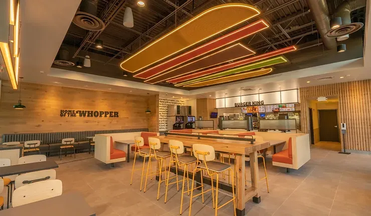 The interior of a burger king restaurant with tables and chairs.