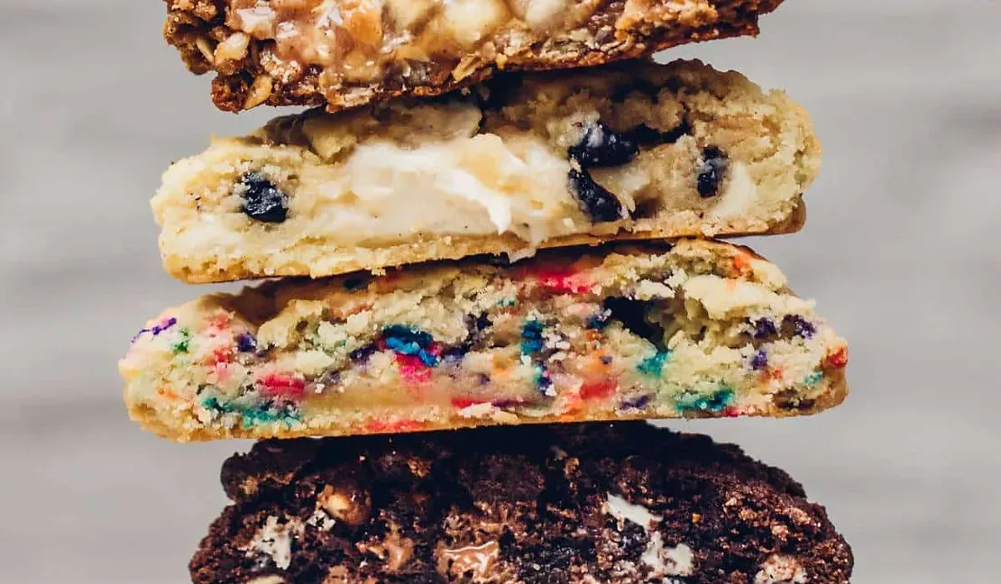 Four different types of cookies are stacked on top of each other on a table.