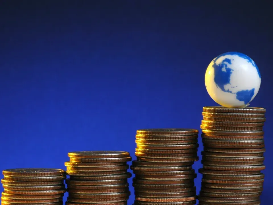 A stack of coins with a small globe on top