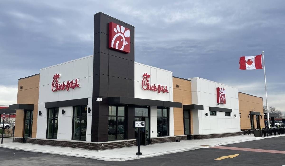 A chick fil a restaurant with a canadian flag flying in front of it.