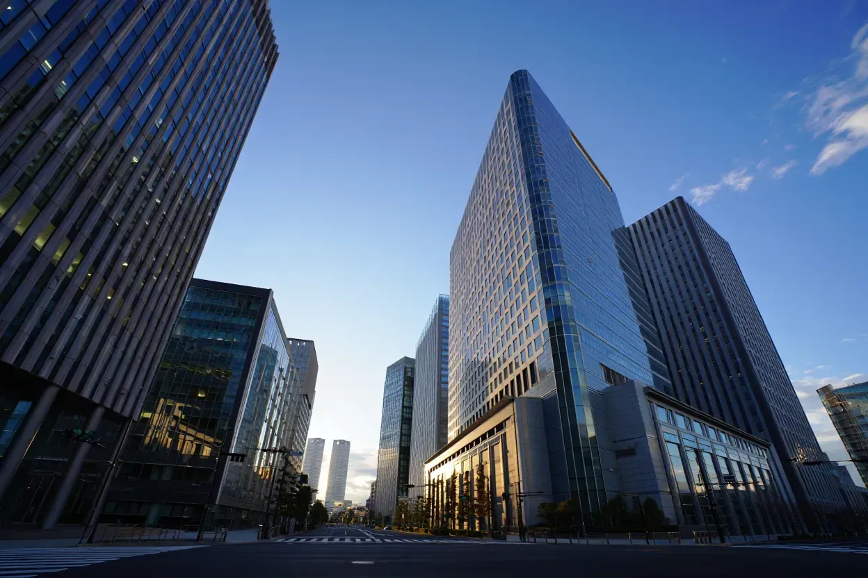 The main entrance of the NuHAA building, featuring a modern glass and stone facade, at sunset.
