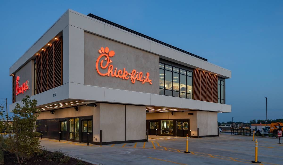 A chick-fil-a restaurant with a parking lot in front of it.