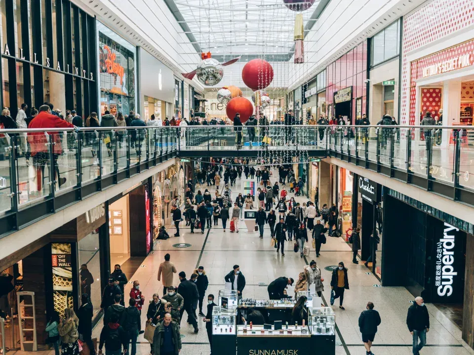 A large group of people are walking through a shopping mall.