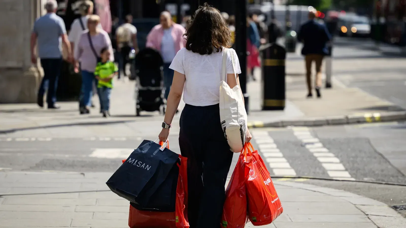 A woman is walking down the street with shopping bags.