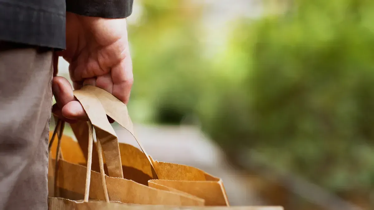 A person is holding a brown paper bag in their hand.