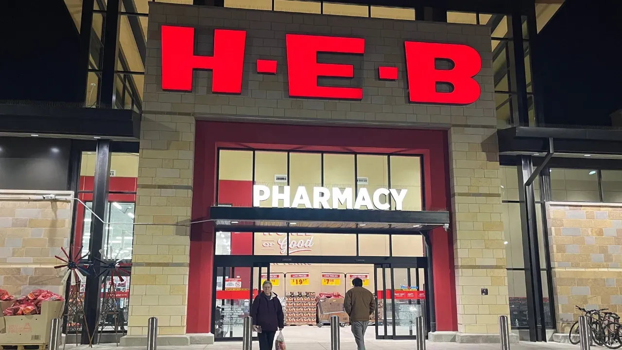 People are walking into a h-e-b pharmacy at night