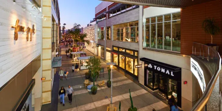 A group of people are walking down a sidewalk in front of a building that says tonal on it.