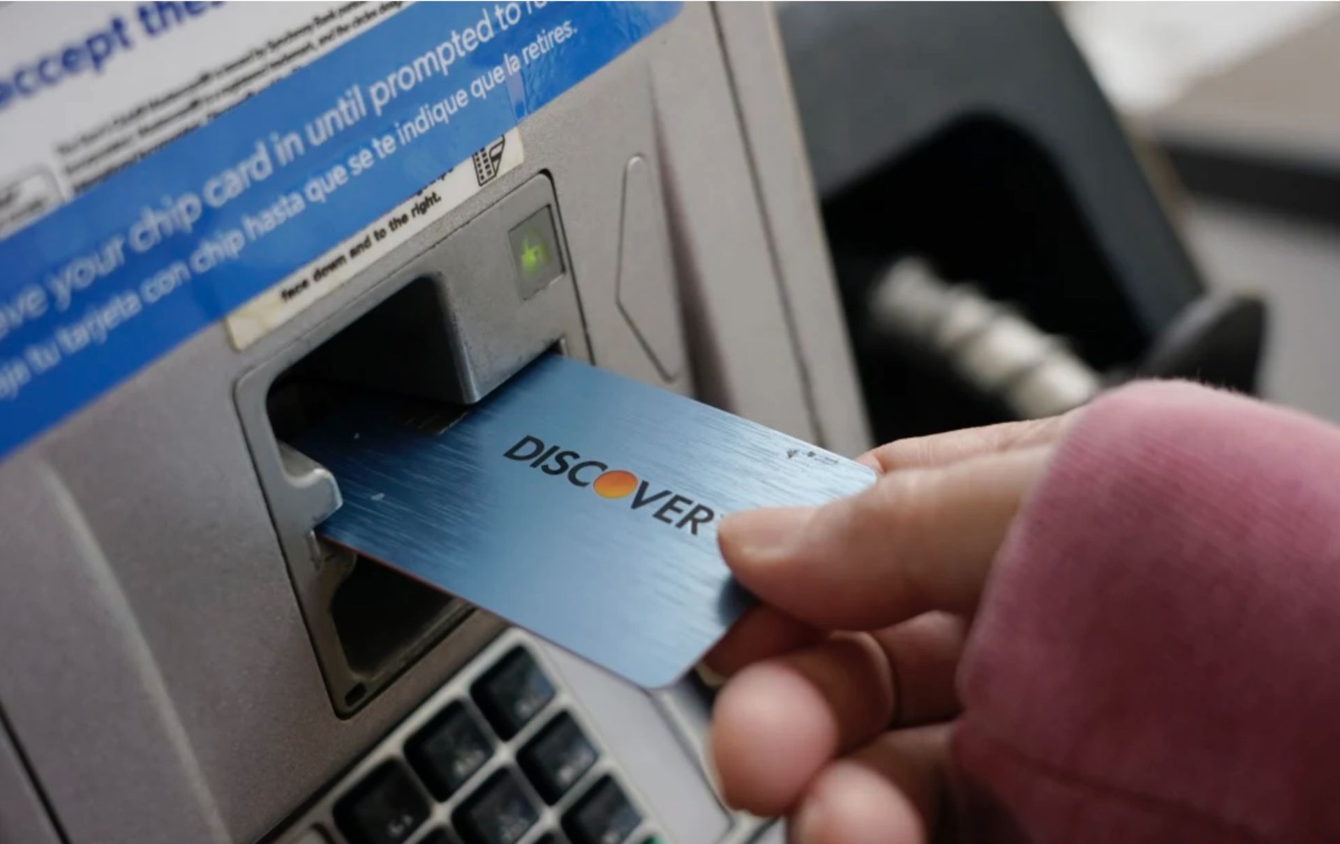 A person is inserting a discover card into an atm machine