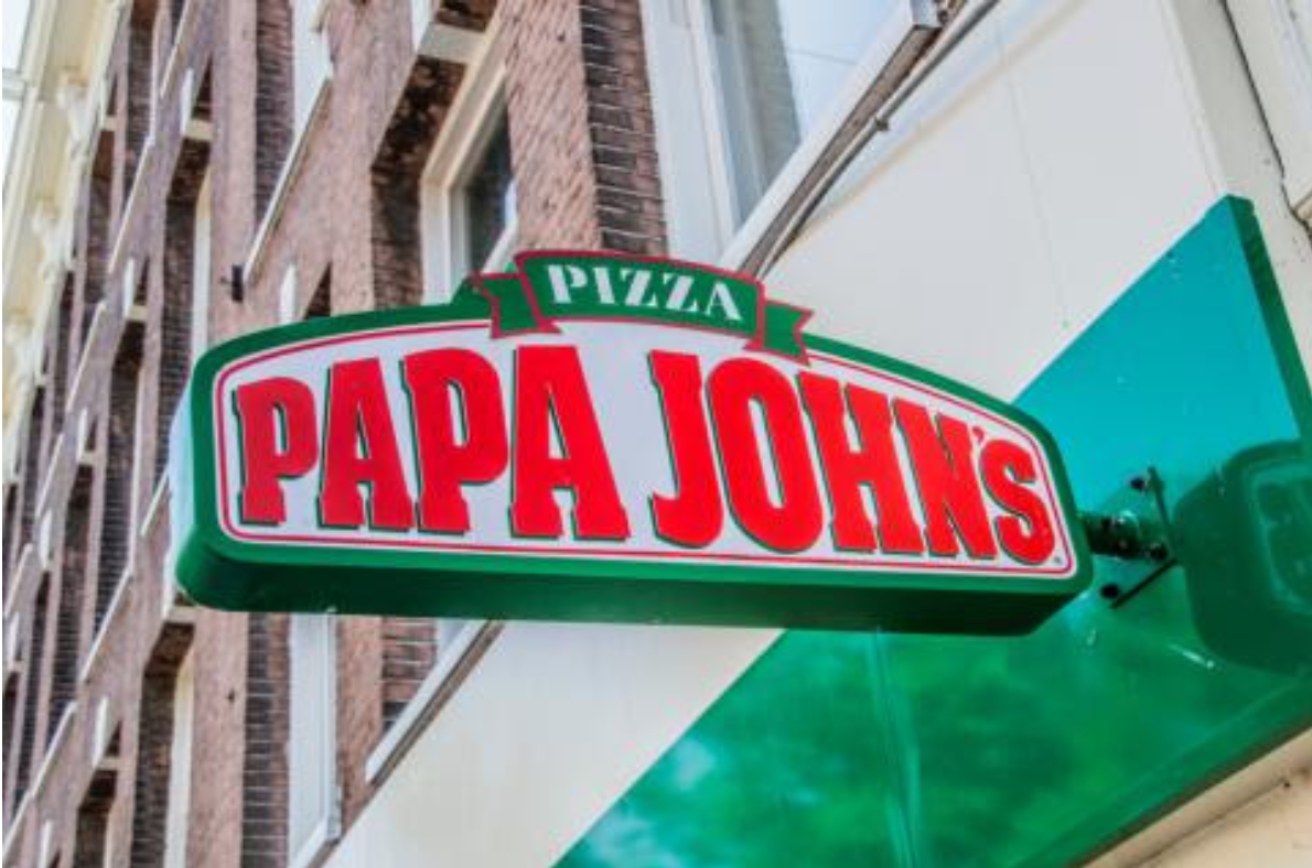 A papa johns pizza sign hangs from the side of a building