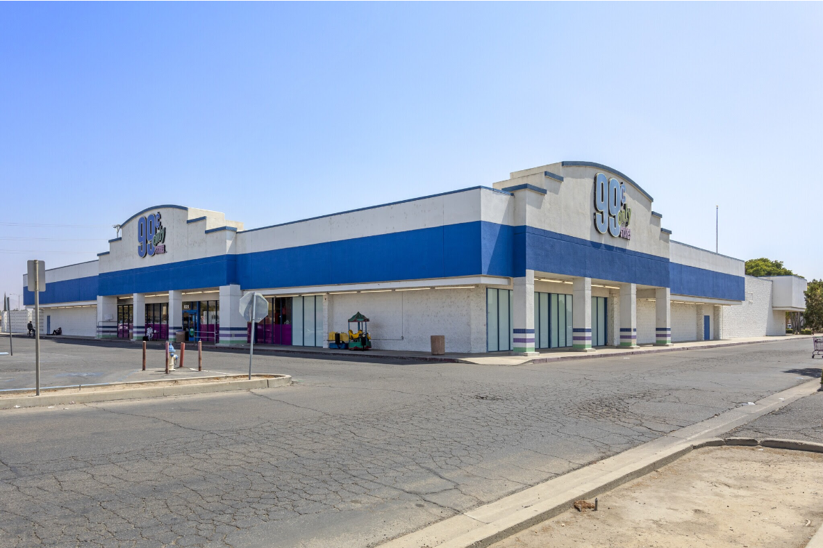 A large white and blue building with a parking lot in front of it.