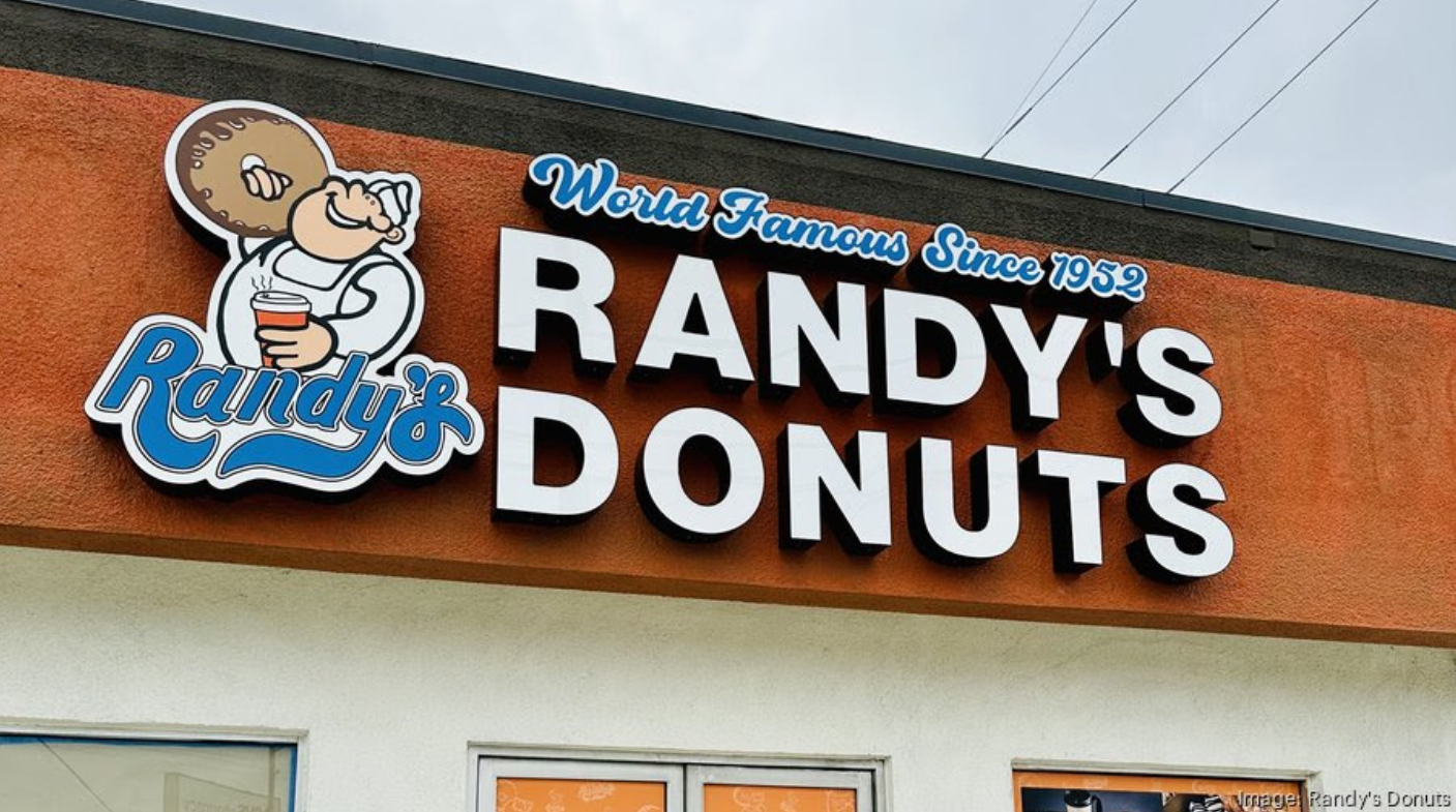 A sign for randy 's donuts with a picture of a man holding a donut