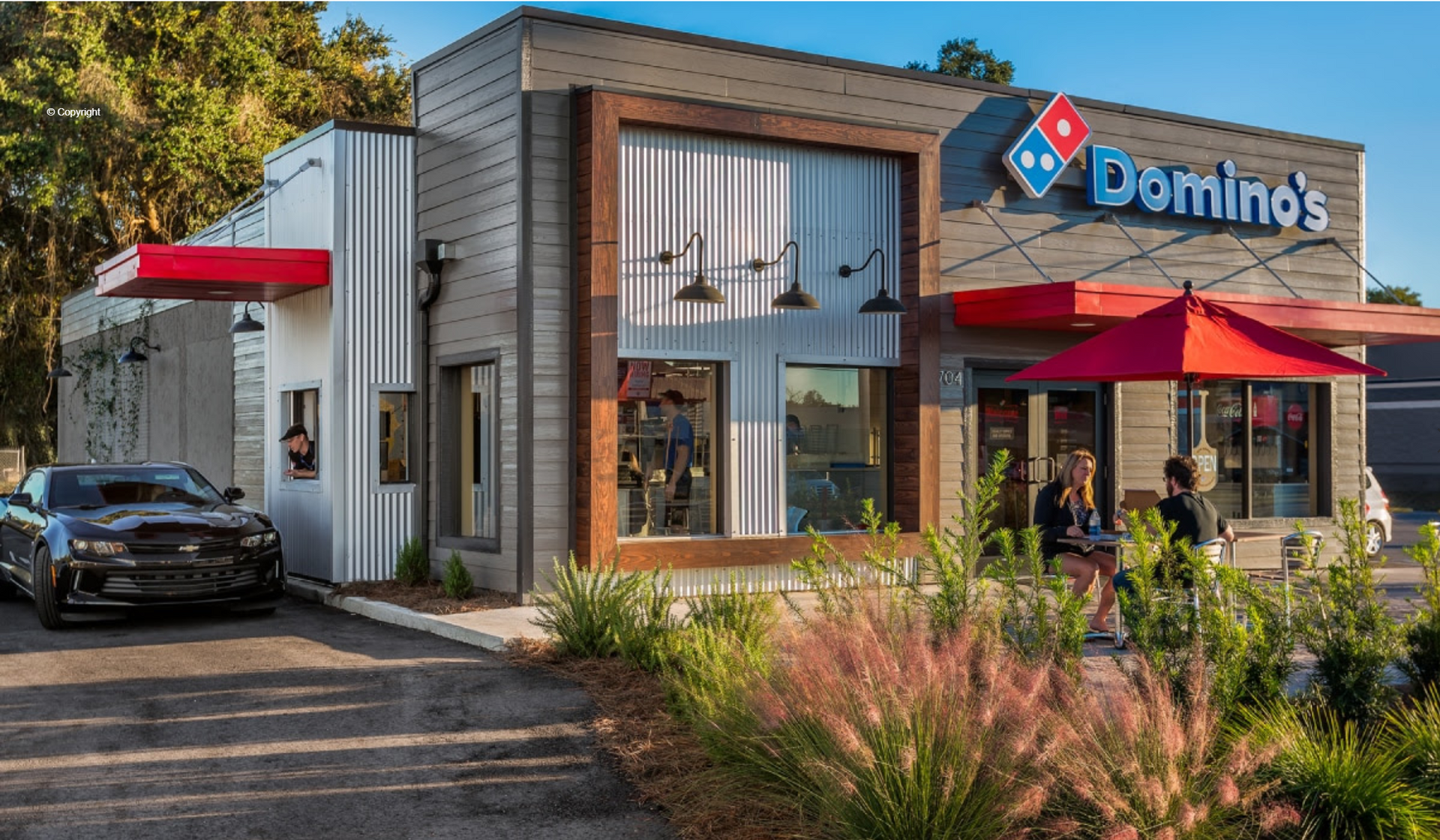 A domino 's pizza restaurant with a car parked in front of it.